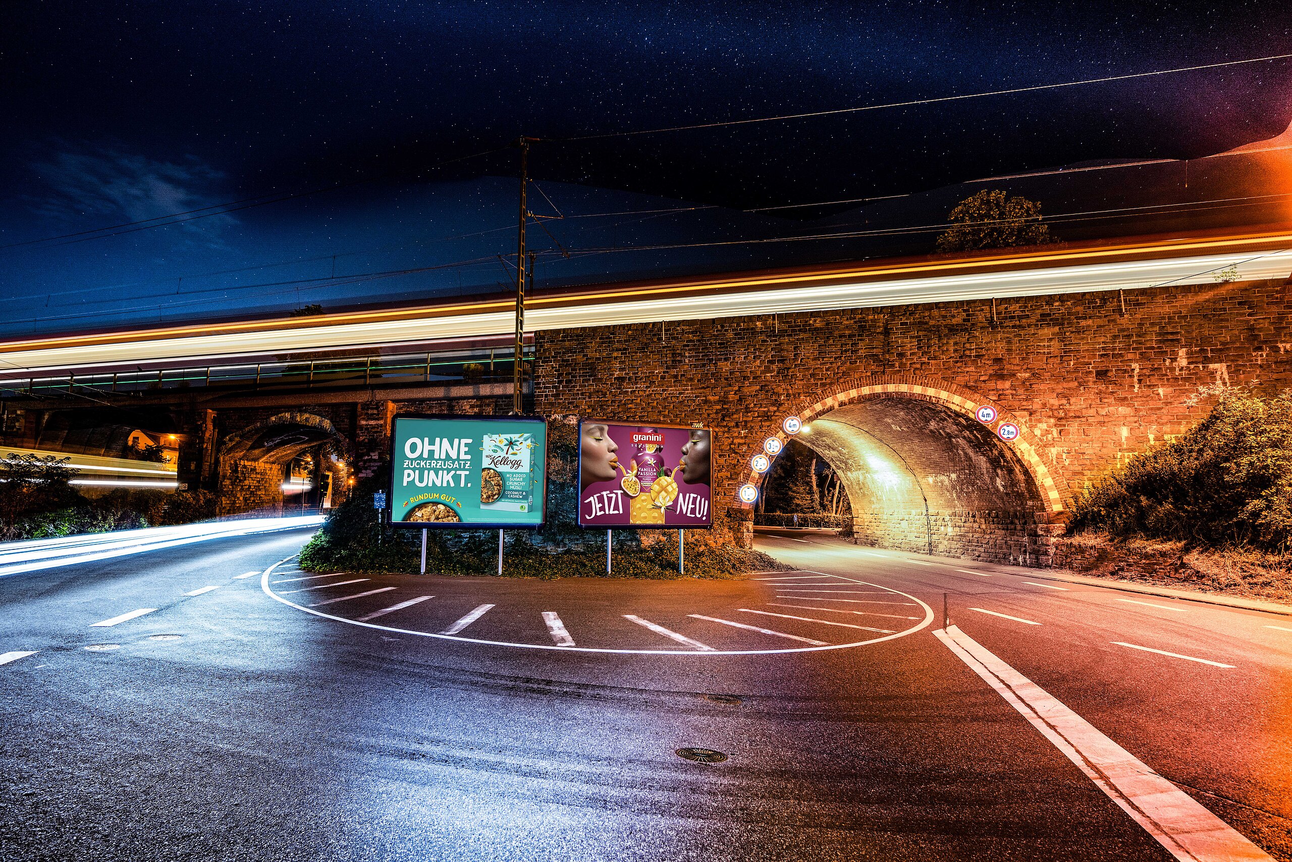 Zwei Großplakate an einer Straßenunterführung bei Nacht.
