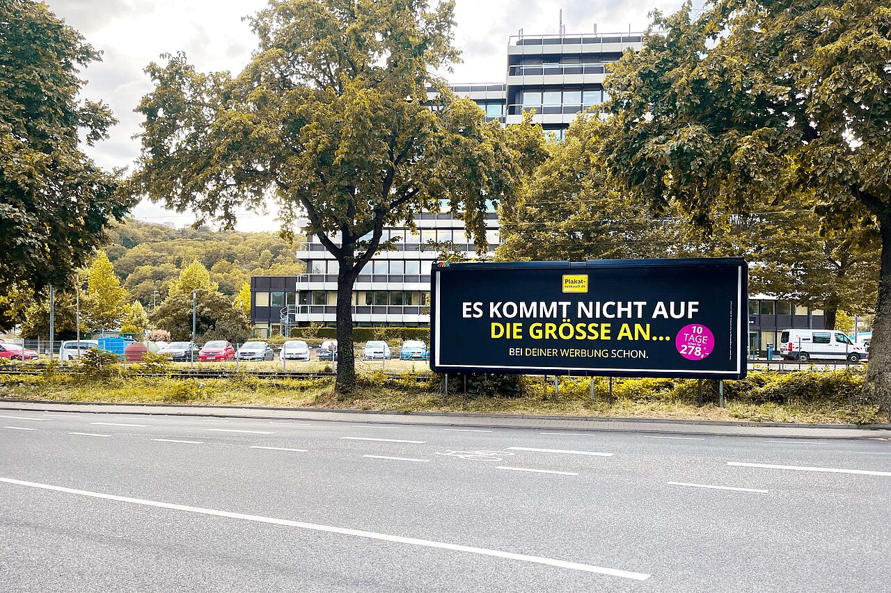 Megastar Plakatwand an einer vielbefahrenen Straße mit dem Slogan 'ES KOMMT NICHT AUF DIE GRÖSSE AN'. Große Werbefläche für hohe Sichtbarkeit und Effektivität.