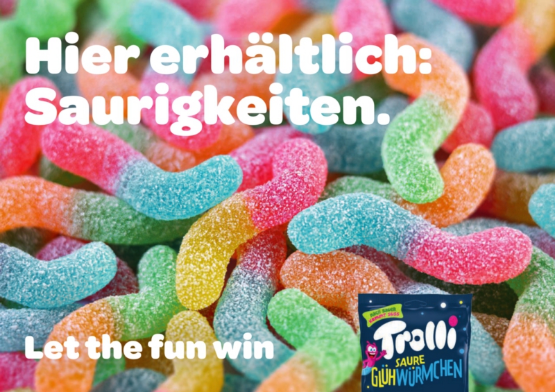 plakat-verkauft.de_lebensmittel_trolli Plakatmotiv der Marke Trolli mit bunten sauren Glühwürmchen-Gummis und dem Werbespruch „Hier erhältlich: Saurigkeiten – Let the fun win“.